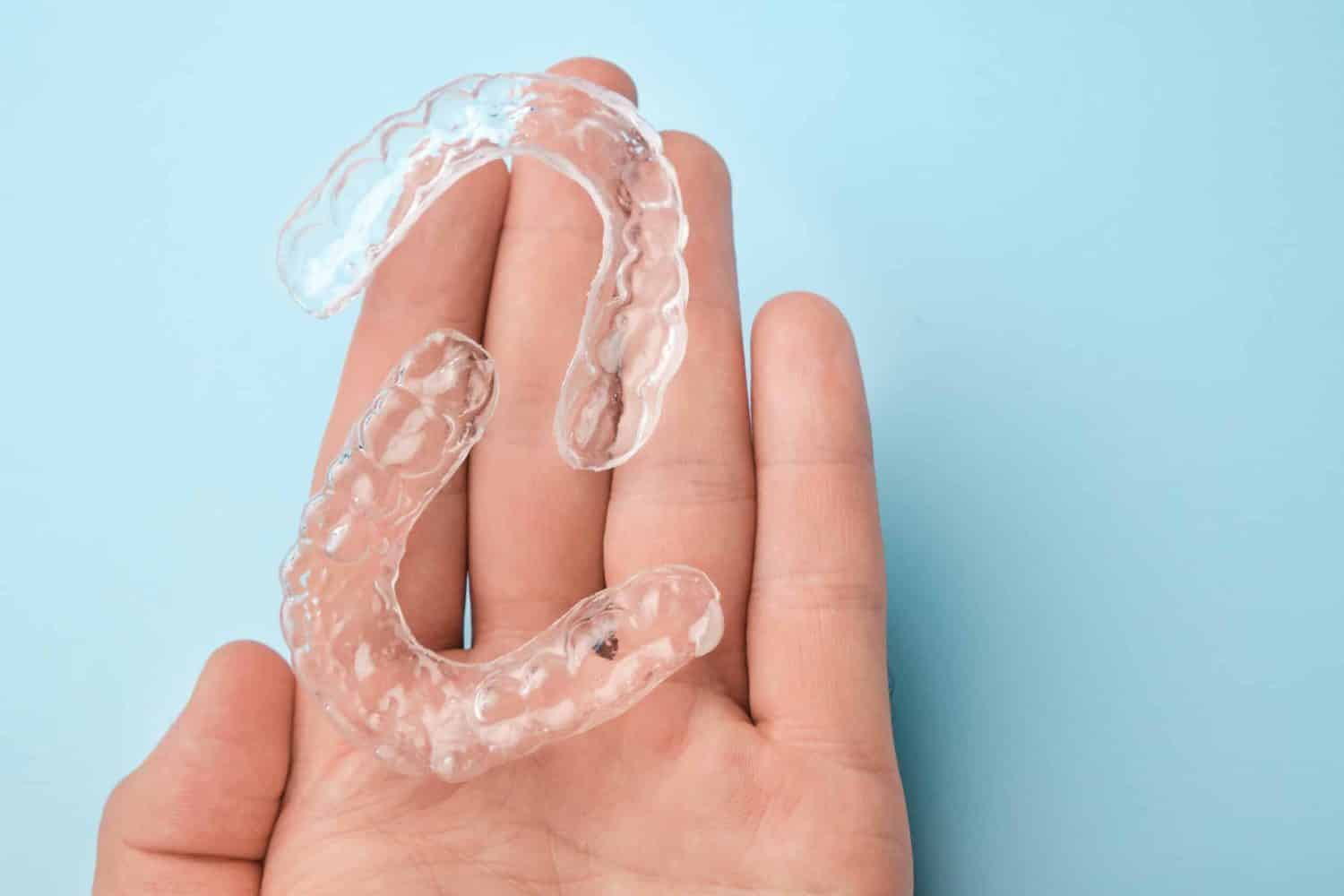 At Chomp Dental, a patient's hand is holding clear aligners.